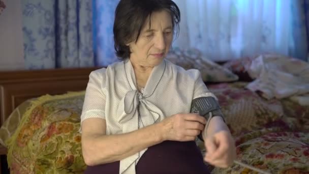 Old woman using blood pressure measurement tool on hand with electronic screen — Stock Video