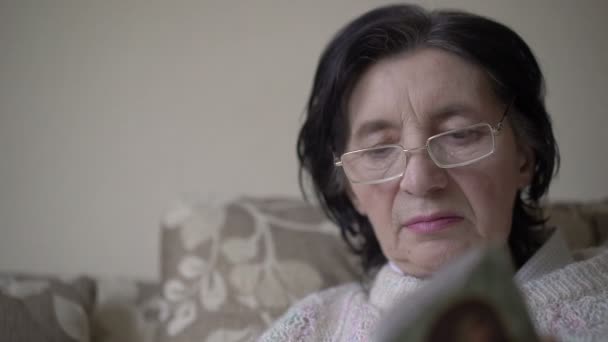 Portrait of mature woman in glasses looking on the prayer book — Stock Video