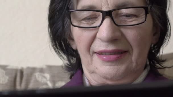 Одинокая бабушка в очках с помощью планшетного компьютера — стоковое видео