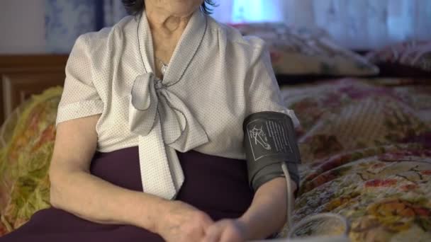 Retrato de anciana en camisa midiendo la presión en la mano — Vídeos de Stock