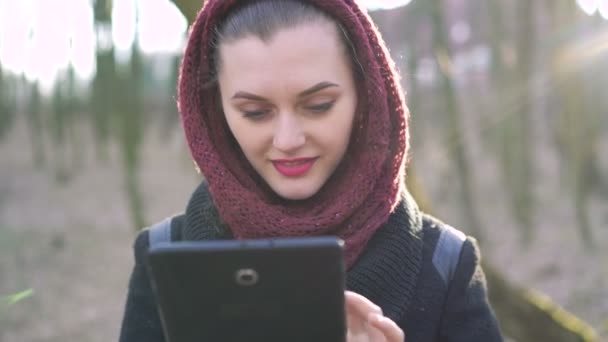 Chica con una tableta en un bosque soleado. 4k — Vídeo de stock