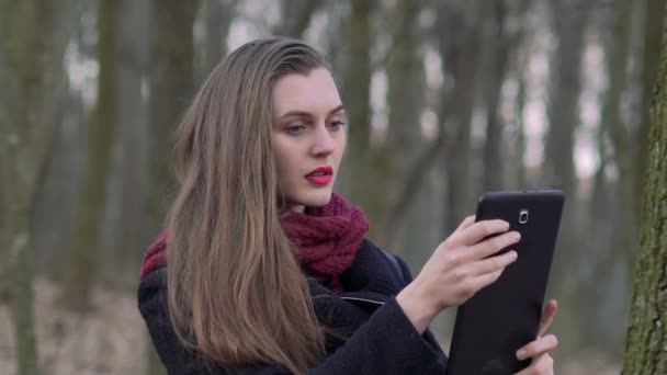Retrato de una chica con una tableta en el bosque. Despacio. — Vídeos de Stock