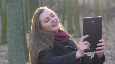 Güzel kız selfie güneşli bir ormanda yapıyor