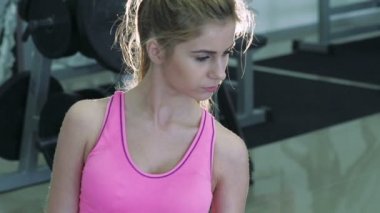 Güzel sarışın egzersizleri dumbbells ile gerçekleştirir. Yavaş yavaş
