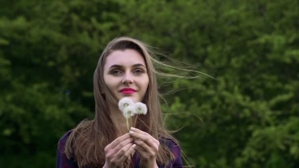 Menina agradável soprando o dente-de-leão buquê no jardim. Movimento lento — Vídeo de Stock