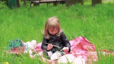 Kız bebek yumurta boyama ve parkta bir çimenlikte gülümseyerek. Yavaş yavaş