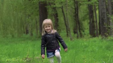 Çimenlerin üzerinde yürüyüş ve gülümseyen küçük şirin kız. Yavaş yavaş