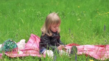 Küçük kız bir çimenlikte boyama. Anne kız şapka giyiyor. Yavaş yavaş