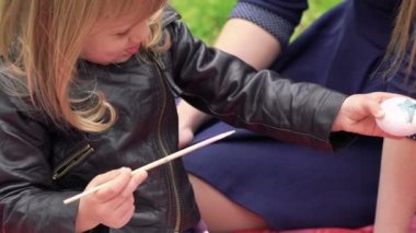 Küçük şirin kız boyama Paskalya yumurtası ailesi Park yakınındaki. Yavaş yavaş