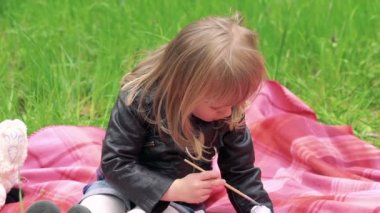 Dekoratif yumurta gösterilen ve bir parkta bir çimenlikte gülümseyen küçük kız. Yavaş yavaş