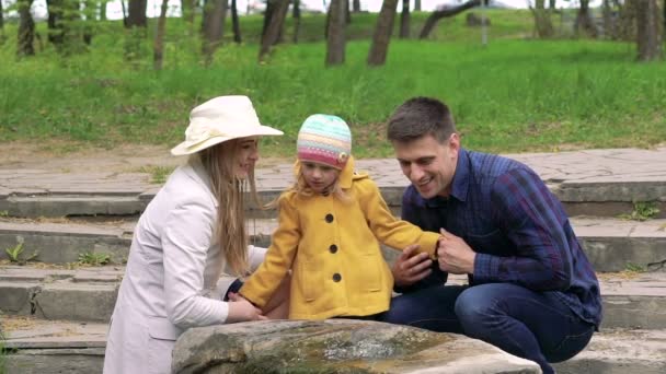 Familia feliz con bebé descansando cerca de la fuente en un parque. Despacio. — Vídeos de Stock