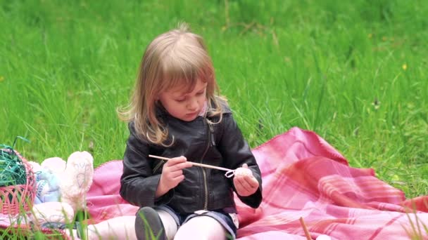 Kleines Mädchen bemalt Ei und lächelt auf einer Wiese im Park. langsam — Stockvideo