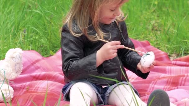Dziecko dziewczynka malowanie jaj na trawnik i uśmiechając się na kamery. Powoli — Wideo stockowe