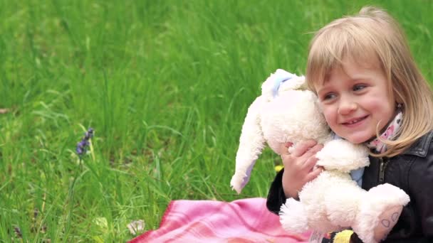 Kleine Mädchen spielen mit Stofftieren auf einer Liegewiese in einem Park. langsam — Stockvideo