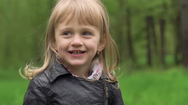 Jolie petite fille blonde souriante dans un parc. Doucement. 