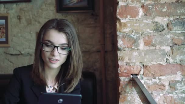 Το χαριτωμένο κορίτσι χρησιμοποιώντας μια ταμπλέτα σε ένα μοντέρνο άνετο καφέ 4k — Αρχείο Βίντεο