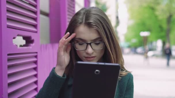 Portret van een jonge vrouw met behulp van een tablet over een straat 4k — Stockvideo