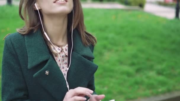 Дівчина використовує телефон і слухає музику з нього на вулиці 4k — стокове відео