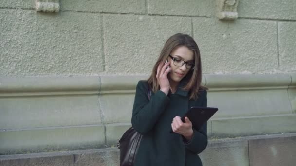 La chica hablando por teléfono móvil, sosteniendo una tableta en la ciudad 4k — Vídeos de Stock