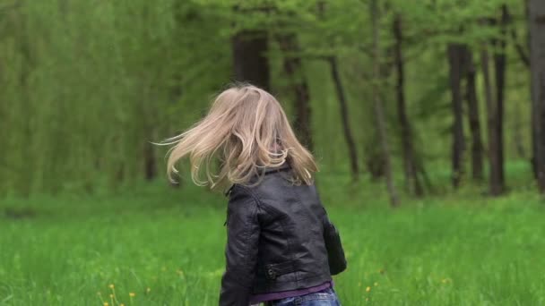 petite fille se retournant, touchant ses cheveux et souriant sur une caméra. Doucement. 
