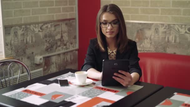 那个漂亮的女孩，在一个现代的舒适咖啡馆 4 k 使用平板电脑 — 图库视频影像