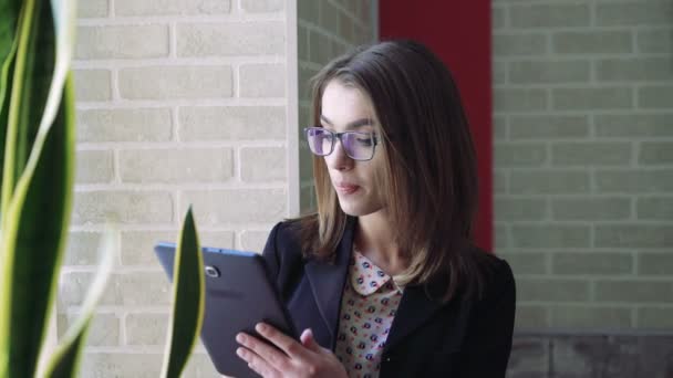 Mujer de negocios usando una tableta cerca de la ventana interior 4K — Vídeos de Stock