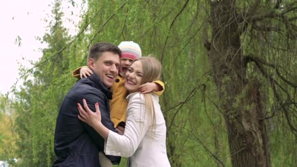 Liten flicka i en föräldrar embracing i parken. Långsamt — Stockvideo