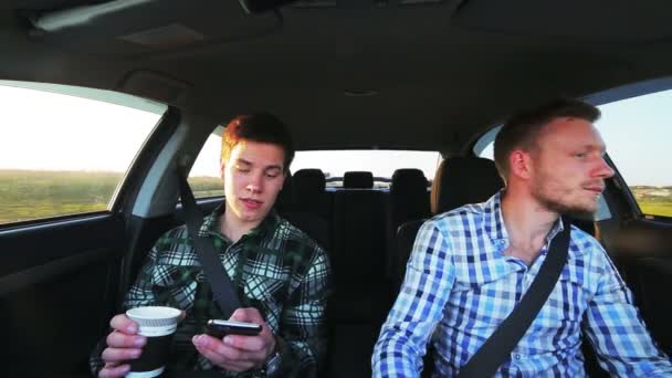 Dois homens dirigindo no carro, bebendo café, usando telefone, sorrindo — Vídeo de Stock