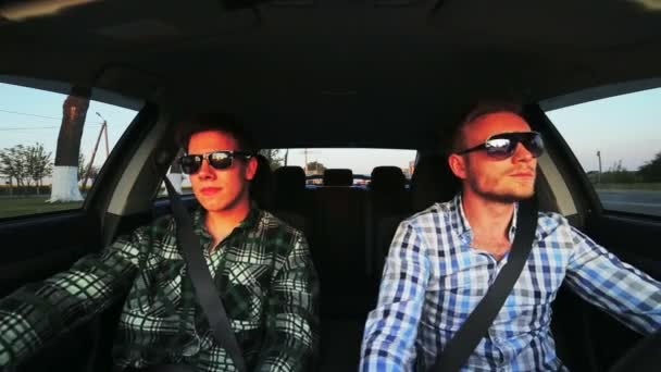 Двое мужчин в солнечных очках в машине, начинают водить машину — стоковое видео