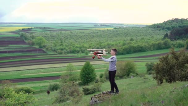 Criança bonito brinca com avião de brinquedo na montanha verde. 4k — Vídeo de Stock