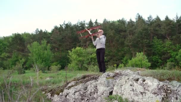 Un bel ragazzo gioca con un aeroplano giocattolo sulla roccia. 4k — Video Stock