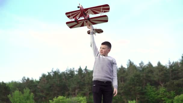 Przystojny chłopak ręka się z samolotu zabawka na porośniętym zielenią zboczu. 4k — Wideo stockowe