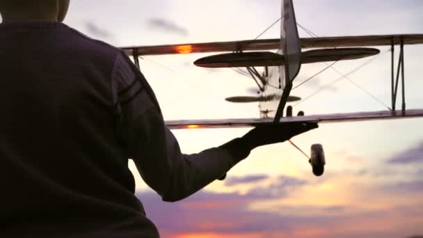 Avión casero en manos de niños sobre un fondo de puesta de sol increíble. 4k — Vídeo de stock