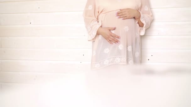 Portrait of happy pregnant stroking her belly on cream background. 4k — Stock Video