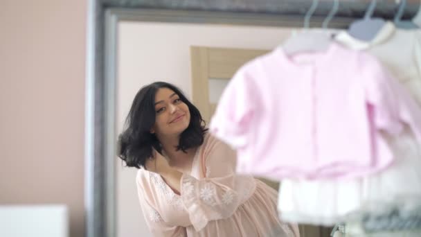Pretty pregnant young woman looking on a mirror in baby room. 4k — Stock Video