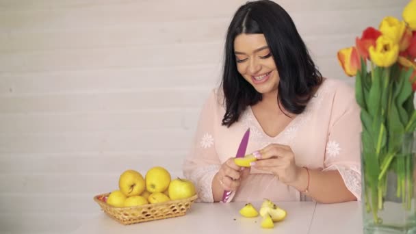 Pregnant woman sliced apple, eating and smiling in the kitchen. 4k — Stock Video