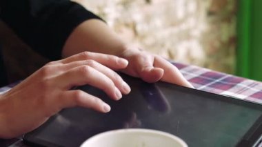 Bir fincan kahve ile bir masada tablet dokunmadan kadın eller görüntülemek