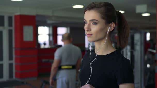 Primer plano de una chica con auriculares en una cinta de correr — Vídeo de stock