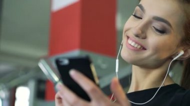 Bir cep telefonu kullanarak müzik salonunda genç gülümseyen kadın.
