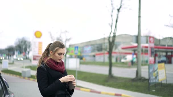 Beautiful girl drinks coffee at a gas station — Stock Video