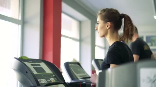 Primer plano de una chica en una cinta de correr. 4k — Vídeos de Stock