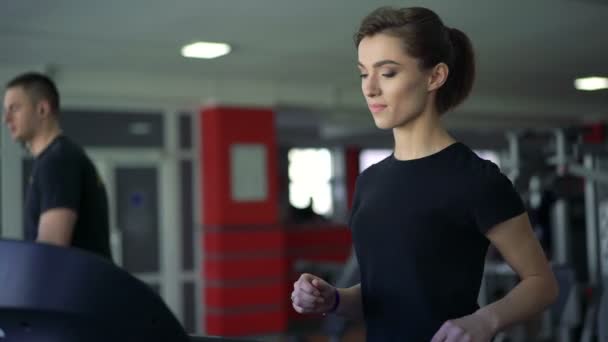 Un hombre y una chica corriendo en la cinta en el gimnasio — Vídeos de Stock