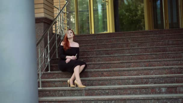 Sexy lady smoking e-cigarette, sitting on the stairs 4k — Stock Video