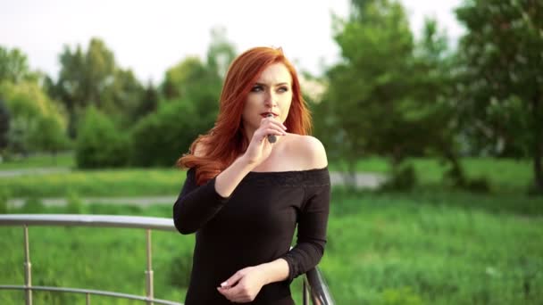 Pretty woman smoking e-cigarette and looking aside on the balcony 4k — Stock Video