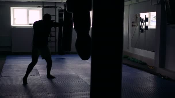 Boxer treina com saco de perfuração no ginásio escuro. 4k — Vídeo de Stock