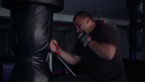 Jeune boxeur s'entraîne sur le sac de boxe dans la salle de gym. 4k — Video