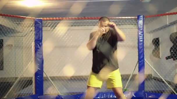 Спортсмен тренируется в боксерской клетке 4K — стоковое видео