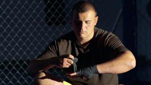 Jovem boxeador embrulhando ligaduras em sua mão antes de lutar no ginásio. Devagar. — Vídeo de Stock