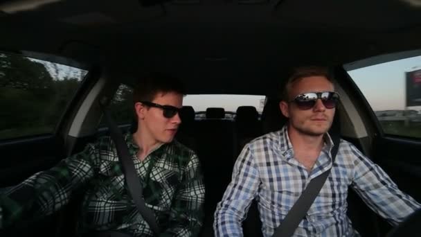 Dos hombres conduciendo rápido en el coche, hablando con gafas de sol — Vídeo de stock