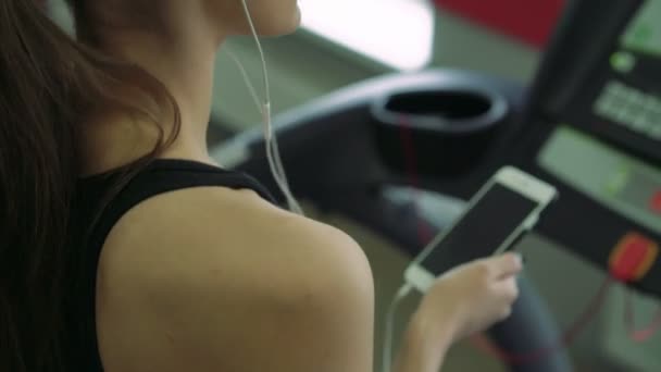 Nahaufnahme eines Mädchens mit Kopfhörern auf einem Laufband. 4k — Stockvideo
